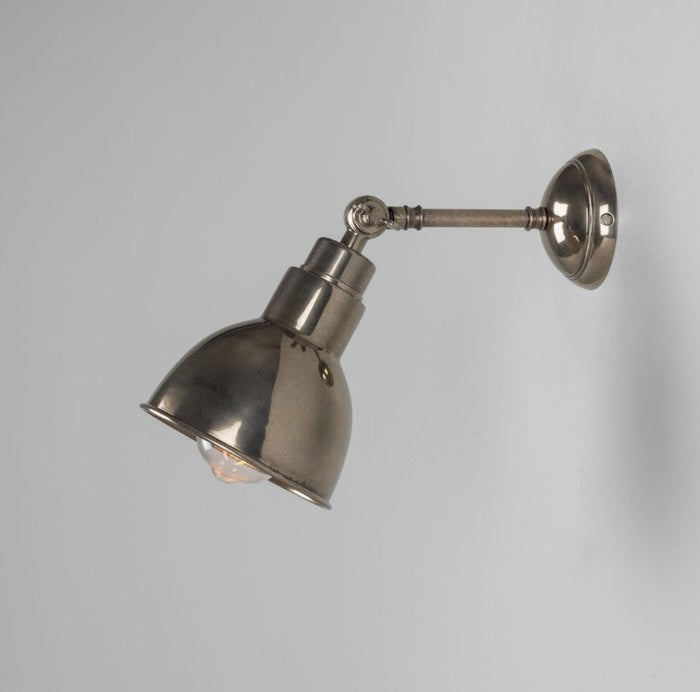 Moorlea brass wall light in aged brass finish with adjustable arm mounted on a white wall