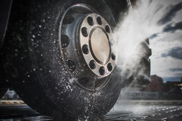 Close-up of a tire with water splashing around it, during a car wash.