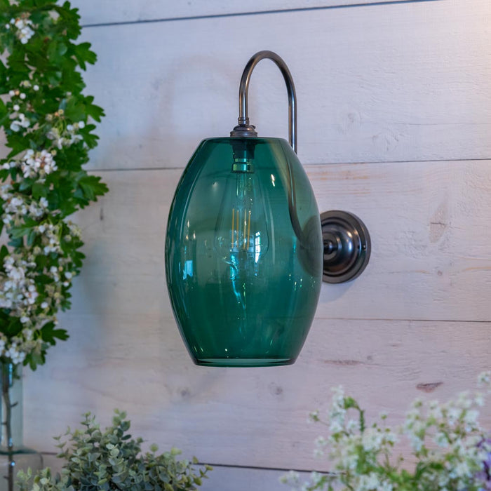 Camber Large Teal Glass Wall Light with antique brass swan neck arm illuminating warm glow in classic interior
