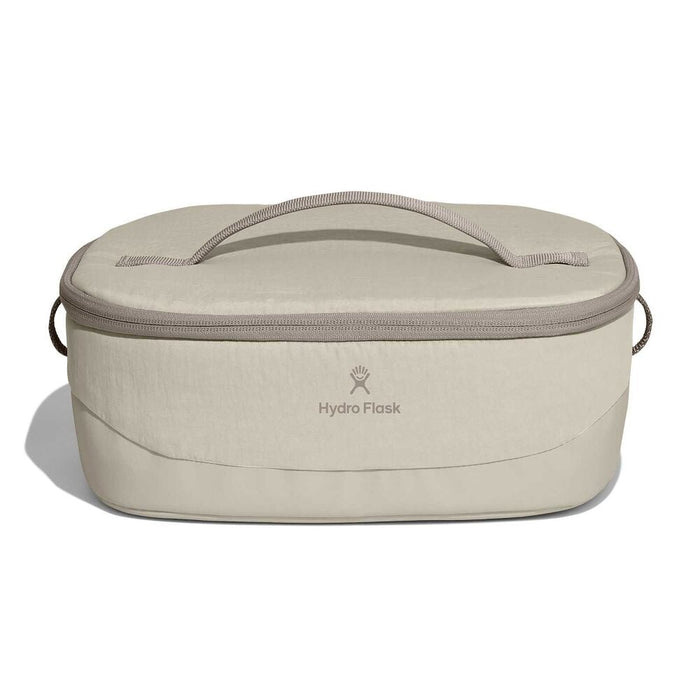Beige Hydro Flask oval insulated bag with zip-around lid, fabric top handle, short side handles, and centered logo. Slightly structured base.