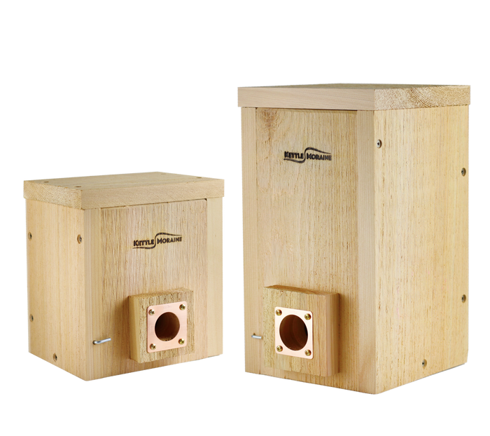 Two cedar roosting boxes, one small and one large, with copper portals on the entrance holes and front panels that open.