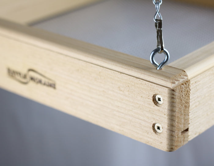 Close up of corner of cedar tray feeder with stainless steel screws and silver chain and clip attached to a silver screw eye.