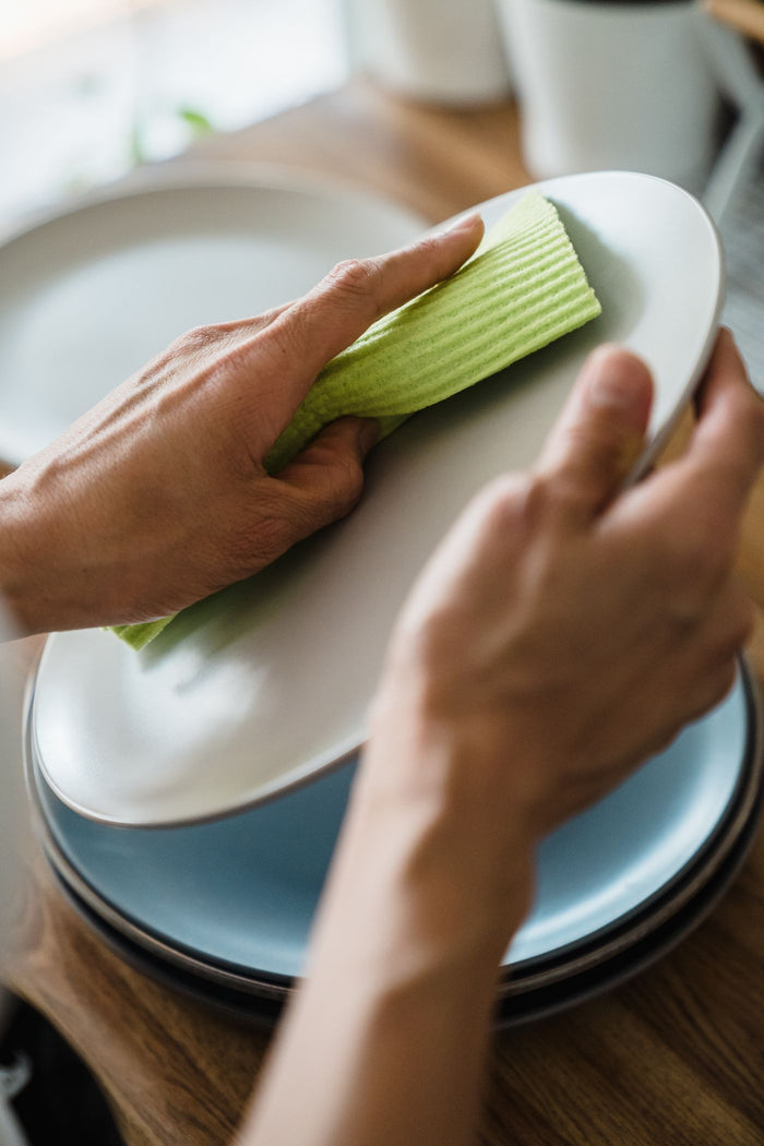 Green cellulose sponge cloth wiping a white plate