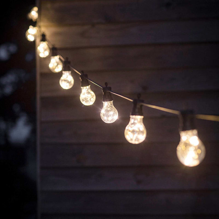 String of illuminated light bulbs against a wooden wall