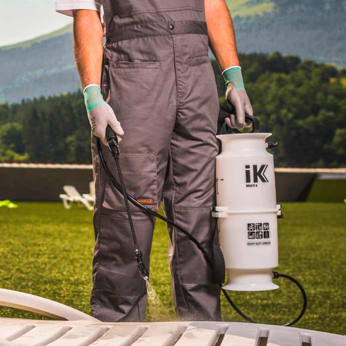 Person holding a pressure washer with IK logo in an outdoor setting