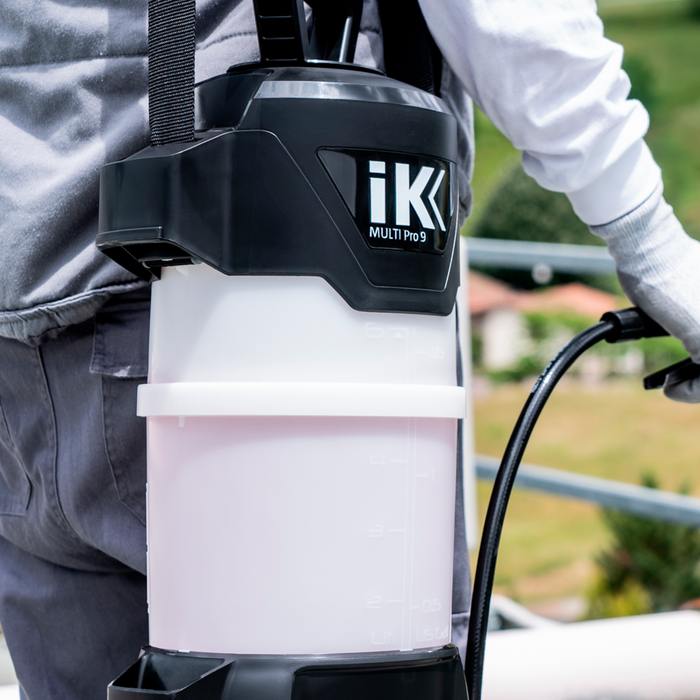Person using an IK sprayer labeled 'iK' with a blurred outdoor background