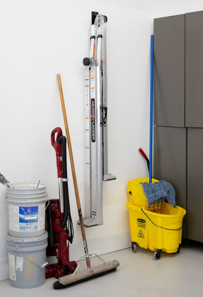Maintenance equipment: red vacuum, ladder, push broom, cleaning buckets, and yellow mop bucket with wringer in storage area.
