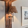 Natural seagrass shade wall light with scalloped edge creating warm, cozy ambient lighting in hallway