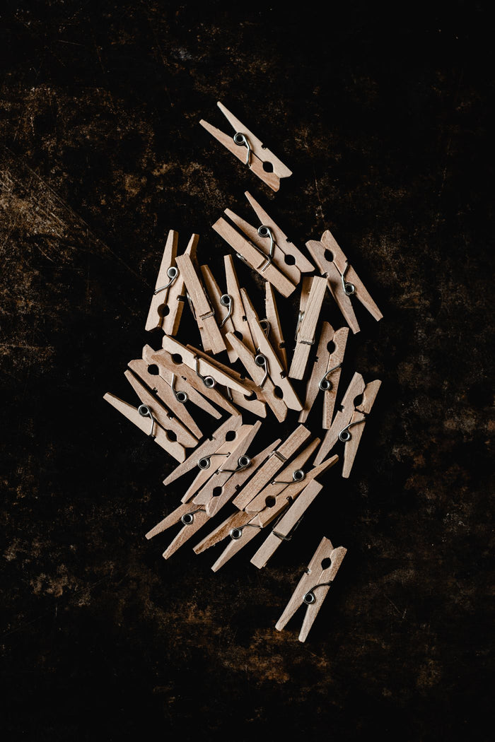 Wooden clothespins scattered on a dark textured background, overhead view