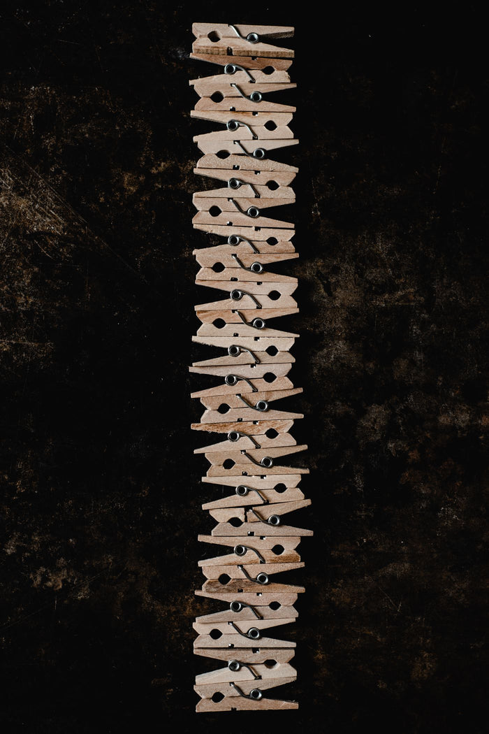 Row of interlocked wooden clothespins on a dark background