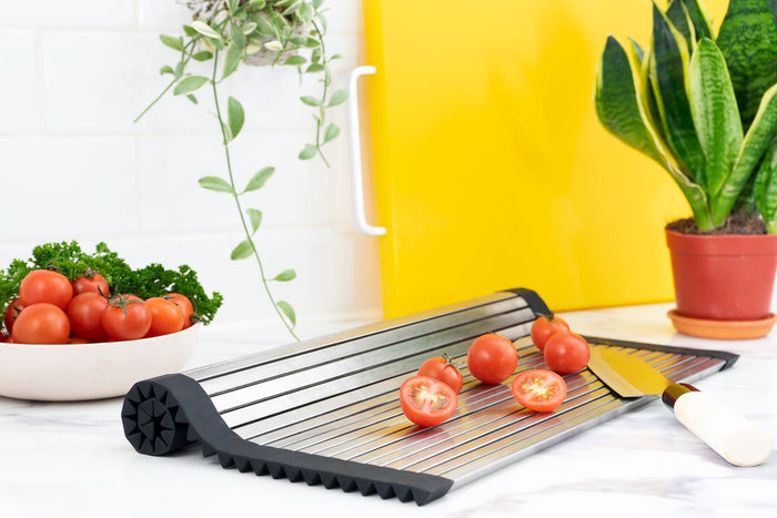 Roll-up dish drying rack on a kitchen counter with cherry tomatoes on it