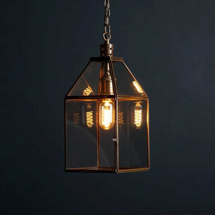 Pooky Carrington Lantern medium pendant light with glass shade and antique brass frame hanging in modern room