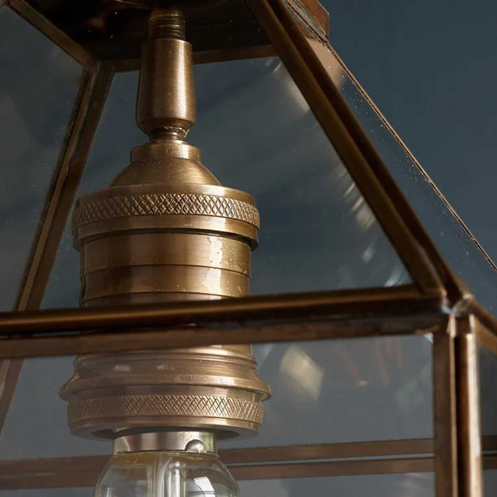 Pooky Carrington Lantern pendant light with glass shade and antique brass frame hanging in a modern interior