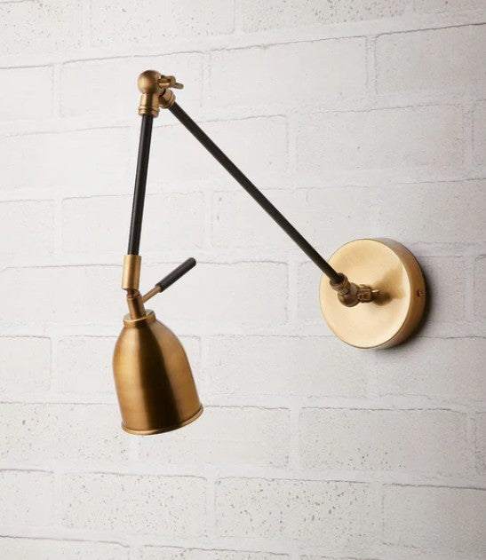 Pooky Pick Brass Wall Light with adjustable arm and warm brass finish mounted on a wall in a modern interior