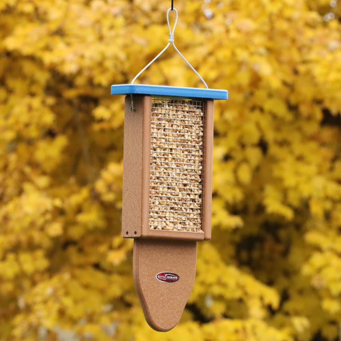 A brown bird feeder with a blue top made of recycled plastic filled with peanuts. Has a wire mesh side. Feeder has a hanging cable and rounded tail prop.
