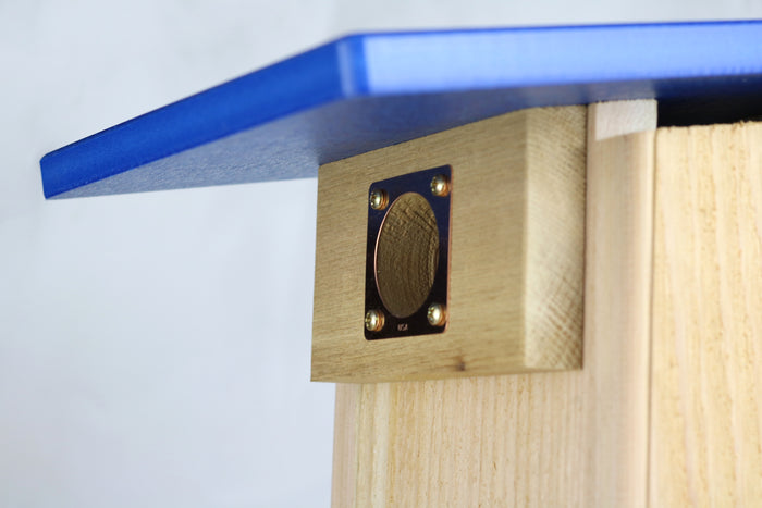 Close up of the copper portal framing the entrance hole of a cedar bird house to protect against predators