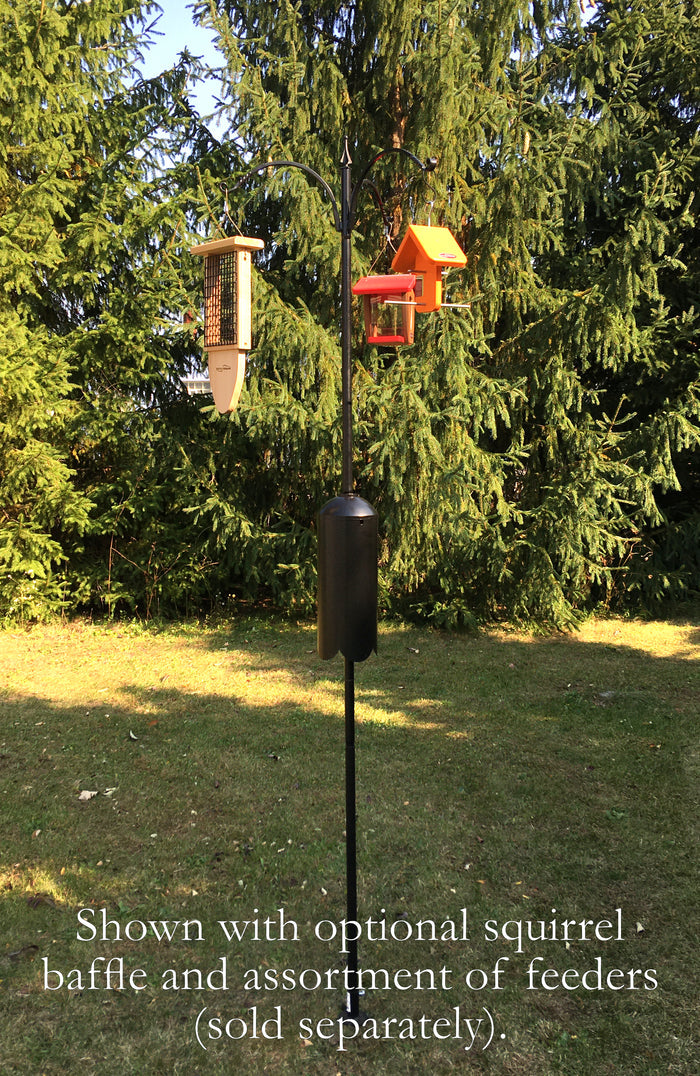 Three arm pole with assortment of bird feeders sold separately. Pole shown with a squirrel baffle and in a yard with pine trees.