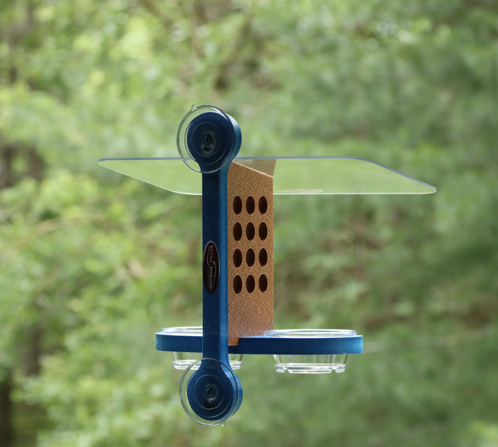 Recycled plastic window mount feeder with 2 suction cups and blue mounting bracket. Has 12 holes on both sides of brown body, a clear acrylic roof, and blue base holds 2 clear cups.